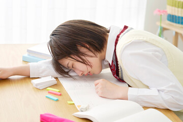 Naklejka premium 自宅で勉強中に居眠りする女子高生