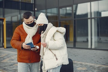 Couple standing outdoors wearing face mask and waiting for travel