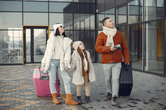 Mother, father and daughter with luggage going from airport terminal