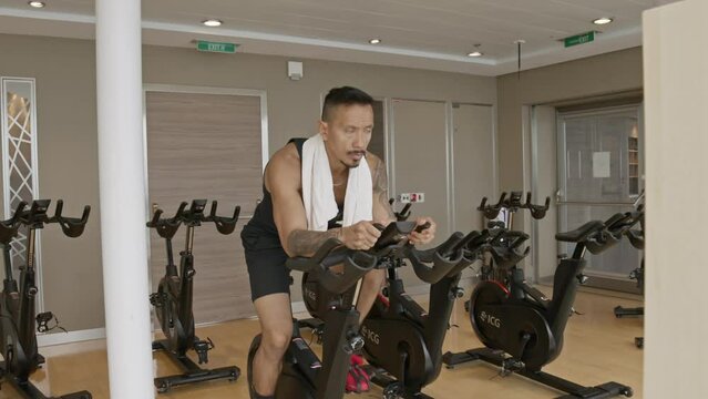 male with tattoos riding a spinning bike 