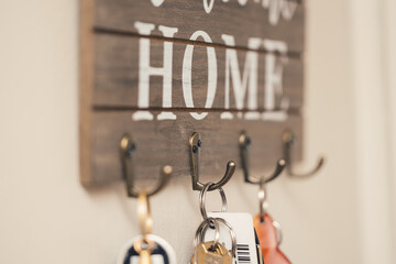 keys hanging on wooden and metal key hook with welcome home message