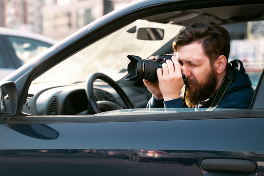 Man paparazzo taking pictures from the car, closeup shot . Private investigator
