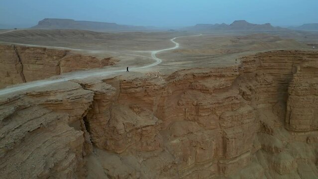 Person standing on cliff edge at Edge Of The World in Saudi Arabia