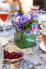 Table setting with flowers. Dinner table flower setting. Purple Pansy colorful flowers on a table