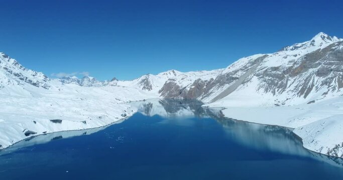 Blue Tilicho Lake in Manang Nepal is surrounded by Mountains covered with snow. Drone slowly moves back to give an adventurous and exciting view of Biggest Lake in the World. 4K