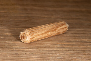 single oak dowel pins on oak  background, dowel pins used to join two pieces of wood, joint, joinery