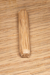 single oak dowel pins on oak  background, dowel pins used to join two pieces of wood, joint, joinery