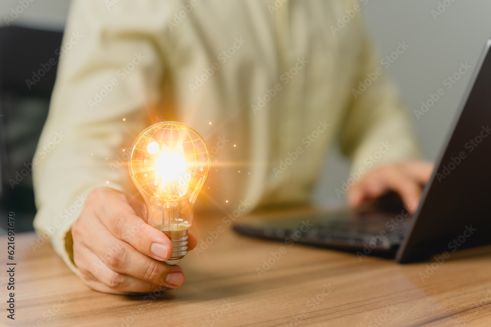 Poster man holding a light bulb while working on a computer laptop to think and generate new ideas through 