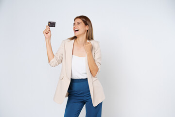 Excited young woman holding credit card and celebrating success isolated on white background.