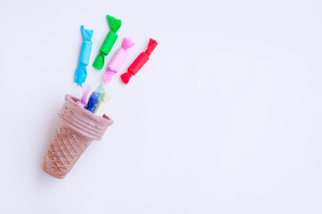 Different kinds of colorful candy out of ice cream cone on gray background, Various candies