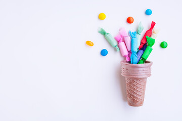 Different kinds of colorful candy out of ice cream cone on gray background, Various candies