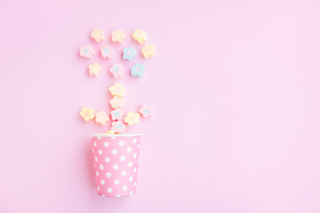 Flower Shaped Marshmallows out of a pink paper cup with white dot on pink background, Multicolored Marshmallows