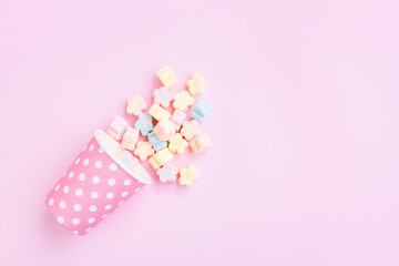 Flower Shaped Marshmallows out of a pink paper cup with white dot on pink background, Multicolored Marshmallows