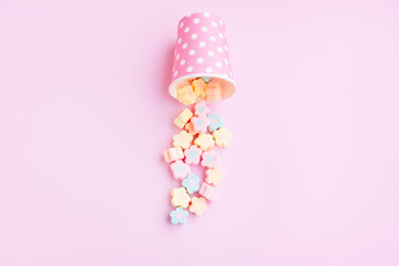 Flower Shaped Marshmallows out of a pink paper cup with white dot on pink background, Multicolored Marshmallows