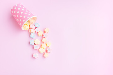 Flower Shaped Marshmallows out of a pink paper cup with white dot on pink background, Multicolored Marshmallows