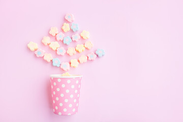Flower Shaped Marshmallows out of a pink paper cup with white dot on pink background, Multicolored Marshmallows