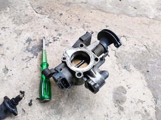 Image of car throttle body on the concrete floor.