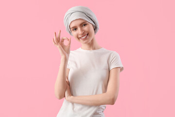 Teenage girl after chemotherapy showing OK on pink background