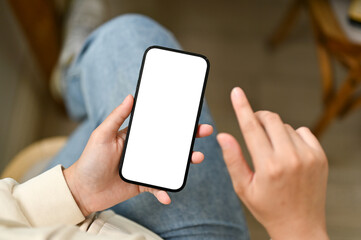 Close-up image of a young Asian woman using her smartphone while sitting at a table