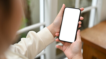 Close-up image of a young Asian woman using her smartphone in a coffee shop.