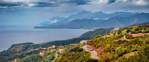 Panorama of typical Albanian countryside. Dramatic landscape of Adriatic shore with asphalt road...