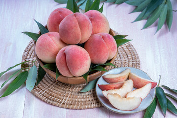 Pink Peach on wooden basket, White Peach with leaf on pink wooden background.