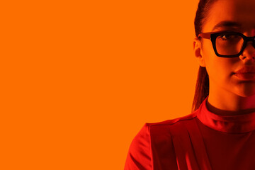 Fashionable young woman wearing glasses on orange background