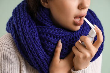 Sick young woman with inhaler on mint background, closeup