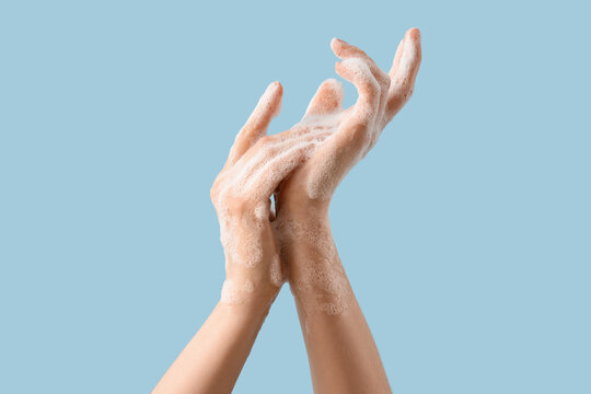 Hands in soap foam on light blue background