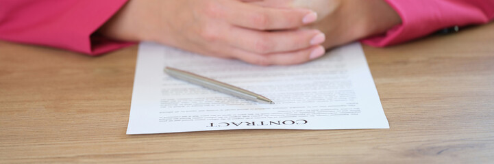 Obraz premium Businesslady sitting at table putting hands on contract agreement