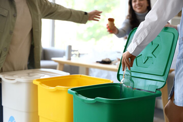 Little girl throwing glass bottle in recycle bin at home, closeup