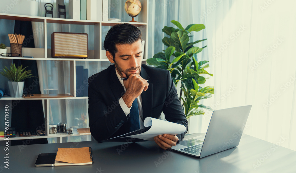 Poster modern professional businessman at modern office desk using laptop to work and write notes. diligent