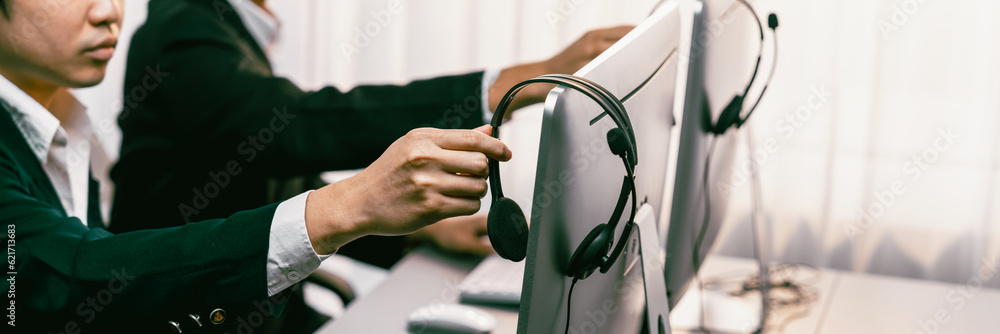 Aufkleber panorama focus hand holding headset on call center workspace desk with blur background of operator t