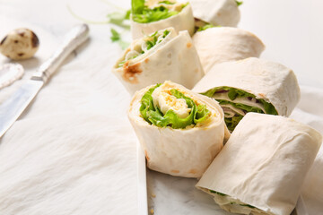 Plate of tasty lavash rolls with egg, onion and greens on white marble background