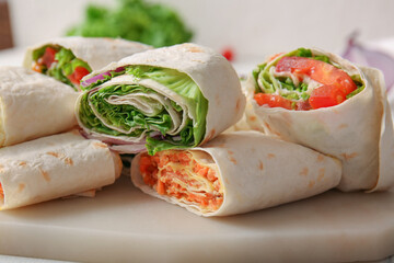 Board of tasty lavash rolls with vegetables on table