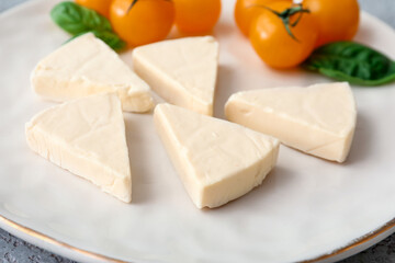 Plate with triangles of tasty processed cheese and cherry tomatoes on table, closeup