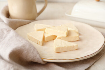 Plate with triangles of tasty processed cheese on light background, closeup