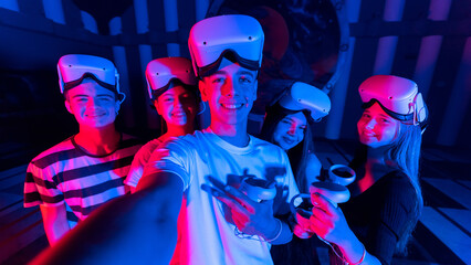 A team of young friends taking selfie while using virtual reality VR equipment on a arena