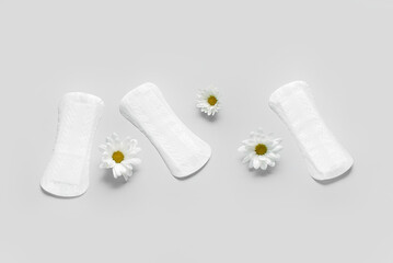 Composition with menstrual pads and chamomile flowers on grey background