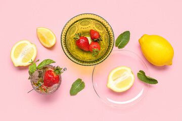 Glass of fresh lemonade with strawberry and lemon on pink background