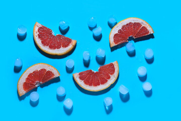 Grapefruit slices with ice cubes on blue background