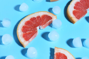 Grapefruit slices with ice cubes on blue background