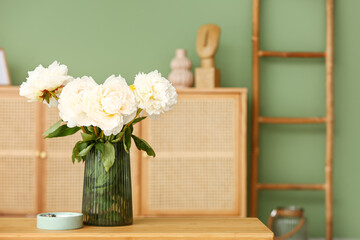 Vase of white peonies with candle on coffee table in living room