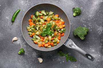 Frying pan with different vegetables on grunge background