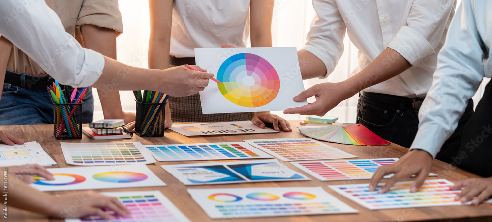 Poster Graphic designer brainstorm logo and graphic art at busy creative studio workshop. Experiment and brainstorm color palette and pattern at workspace table for creative design. Panorama shot. Scrutinize