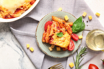 Plate and baking dish of pasta with tomato sauce on white background