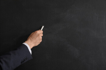 Fototapeta premium Male teacher writing on blackboard, closeup
