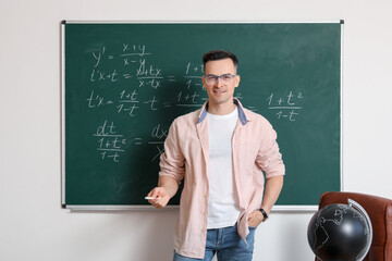 Male Math teacher near chalkboard in classroom