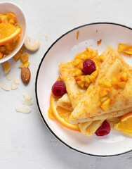 Crepe suzette with orange sauce and raspberry for a delicious breakfast.