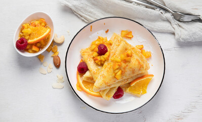 Crepe suzette with orange sauce and raspberry for a delicious breakfast.